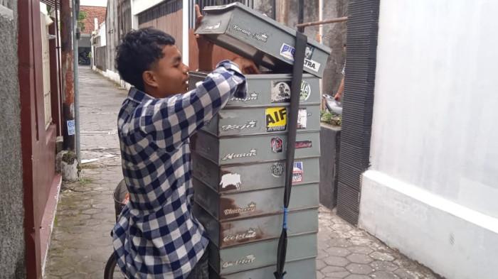 Daud tengah mengambilkan roti hangat untuk pembeli di Jalan Prawirotaman, Selasa (18/11/2025).