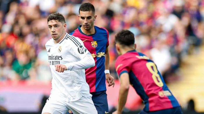 Valverde yang sedang menguasi bola dan dikepung dua pemain barca.