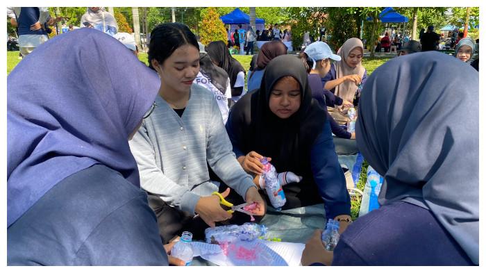 BUAT ECOBRICK - Relawan Turun Tangan Palangka Raya duduk melingkar di atas terpal biru saat membuat ecobrick dari sampah plastik dan kertas bekas, di Jalan Yos Sudarso depan Hotel Dandang Tingang, Palangka Raya, Minggu (28/9/2025).