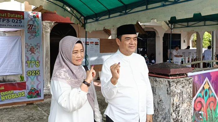 Kompak Kenakan Kemeja Putih Rojikinor dan Istri Coblos di TPS 025 Jalan Sangga Buana I Palangkaraya