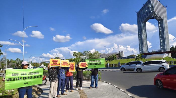 MENGGELAR AKSI - Walhi Kalteng bersama anggota organisasi menggelar aksi di Palangka Raya, Minggu (16/11/2025). Mereka menyuarakan bahwa solusi iklim yang ditawarkan COP30 adalah solusi palsu.