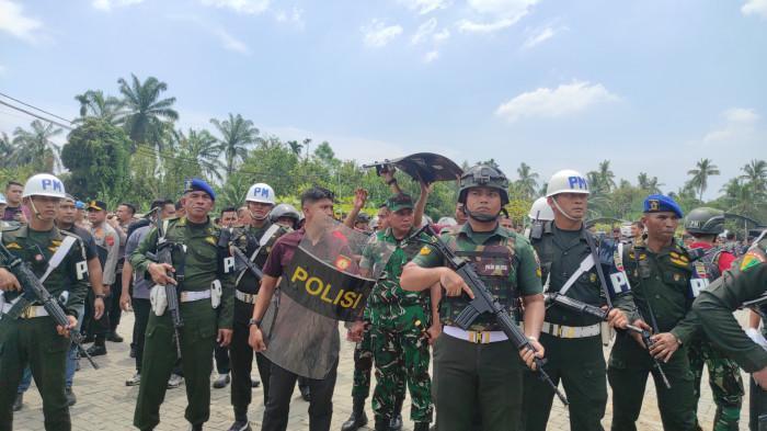 MARKAS GRIB DIBONGKAR - Momen Pangdam I Bukit Barisan Mayjen Rio Firdianto dilindungi ajudannya menggunakan tameng bertuliskan 'Polisi' agar terhindar dari hujan batu ormas yang menolak perobohan markas GRIB Jaya di Desa Namorubejulu, Kecamatan Kutalimbaru, Kabupaten Deli Serdang, Kamis (14/8/2025).