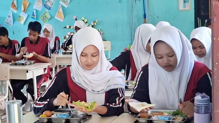 PENERAPAN MBG - Ilustrasi pelajar yang menikmati hidangan makanan dari program Makan Bergizi Gratis (MBG) di SMP Negeri 2 Tanah Grogot, Kabupaten Paser, Kalimantan Timur, Jumat (19/9/2025).