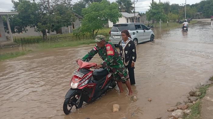 Seorang-Babinsa-membantu-pengendara-melewati-banjir-yang-menggenangi-jalan-raya.jpg