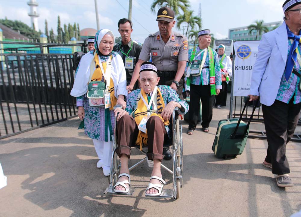 BERITA FOTO - Anggota Polisi Dorong Calhaj Lansia Pakai Kursi Roda di Asrama Haji