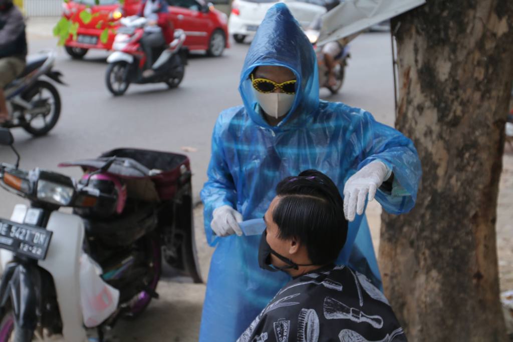 Cara Unik Tukang Cukur Keliling di Bandar Lampung, Pakai 'Baju Hazmat' dari Jas Hujan