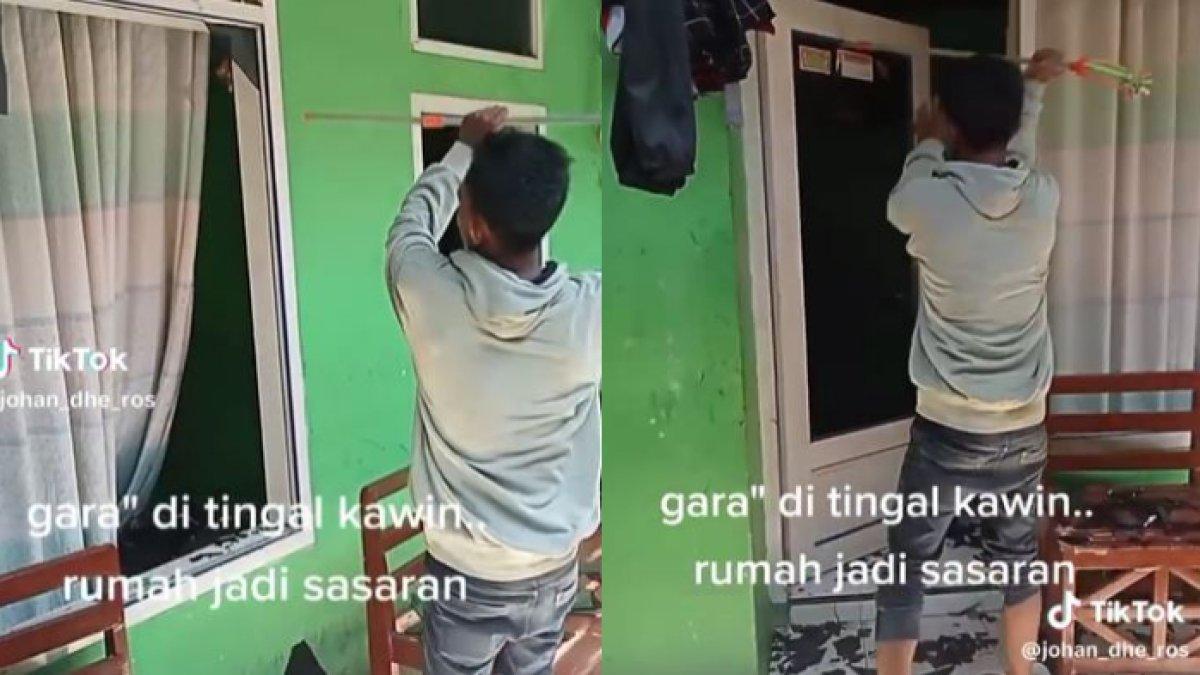 Seorang-pria-berjaket-abu-sedang-memecahkan-jendela-rumahnya-sendiri.jpg