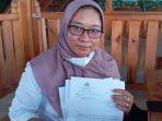 Dwi-Eni-Purwanti-guru-BK-SMPN-1-Camplong-Sampang-menunjukkan-surat-penyidikan.jpg
