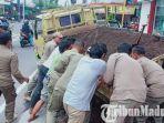 anggota-satpol-pp-bersama-warga-masyarakat-mengangkat-truk-yang-terperosok-lubang-trotoar.jpg