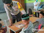 bhabinkamtibmas-polsek-kadur-bripka-h-faizol-amir-saat-menenangkan-salah-satu-siswa-sd.jpg