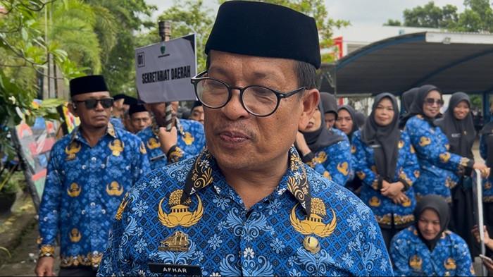 PPPK MAROS - Afhar, seorang honorer Sekretariat Daerah (Setda) Maros usai menerima SK Pegawai Pemerintah dengan Perjanjian Kerja (PPPK) paruh waktu di halaman kantor bupati Maros, Selasa (30/12/2025). Afhar akhirnya dapat mengenakan baju korpri biru setelah penantian panjang selama 22 tahun ini.