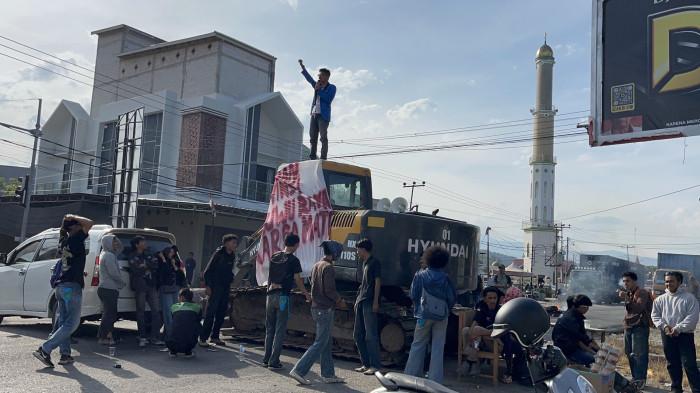 LUWU RAYA - Masyarakat dan mahasiswa unjuk rasa di simpang empat Padang Sappa, Jalan Trans Sulawesi, Kecamatan Ponrang, Kabupaten Luwu, Sulawesi Selatan, Senin (26/1/2026). Mereka memblokade jalan dengan memarkir ekskavator di tengah jalan utama tersebut. (