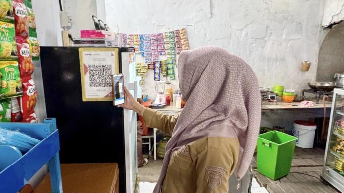SCAN QRIS- Mulianti, guru SMP, membayar melalui QRIS BRI untuk pembayaran di sebuah warung. Mulianti menyampaikan QRIS mempermudah pembayaran Via QRIS.