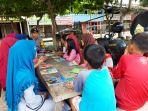 bripda-yusran-dikerumuni-anak-anak-ketika-berpustaka-keliling-di-wilayah-tugasnya.jpg