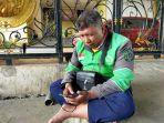 salah-seorang-driver-ojol-rusman-sedang-menunggu-orderan-di-bawah-terowongan.jpg