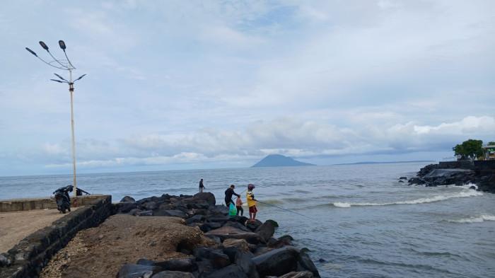 MANCING - Sejumlah orang memancing di pasir putih samping Kawasan Megamas, Manado, Sulawesi Utara, Minggu (15/2/2026). Mereka mengisi waktu luang dan melepas penat.