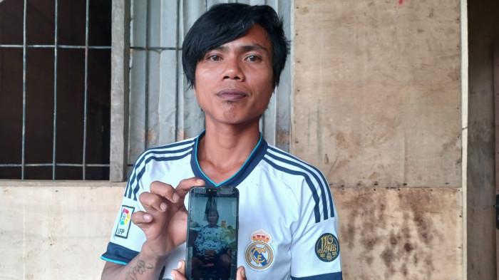 NELAYAN HANYUT - Alexander Rompas menunjukkan foto ayahnya, Charles Rompas (66), di Griya Sea Lestari 5, Minahasa, Sulawesi Utara, Selasa (16/12/2025). Charles adalah nelayan yang hanyut dari Teluk Manado hingga Papua.