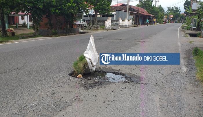 Ditutupi Batu dan Karung, Lubang Jalan di Motoboi Kecil Kotamobagu Sulut Dikeluhkan Pengendara