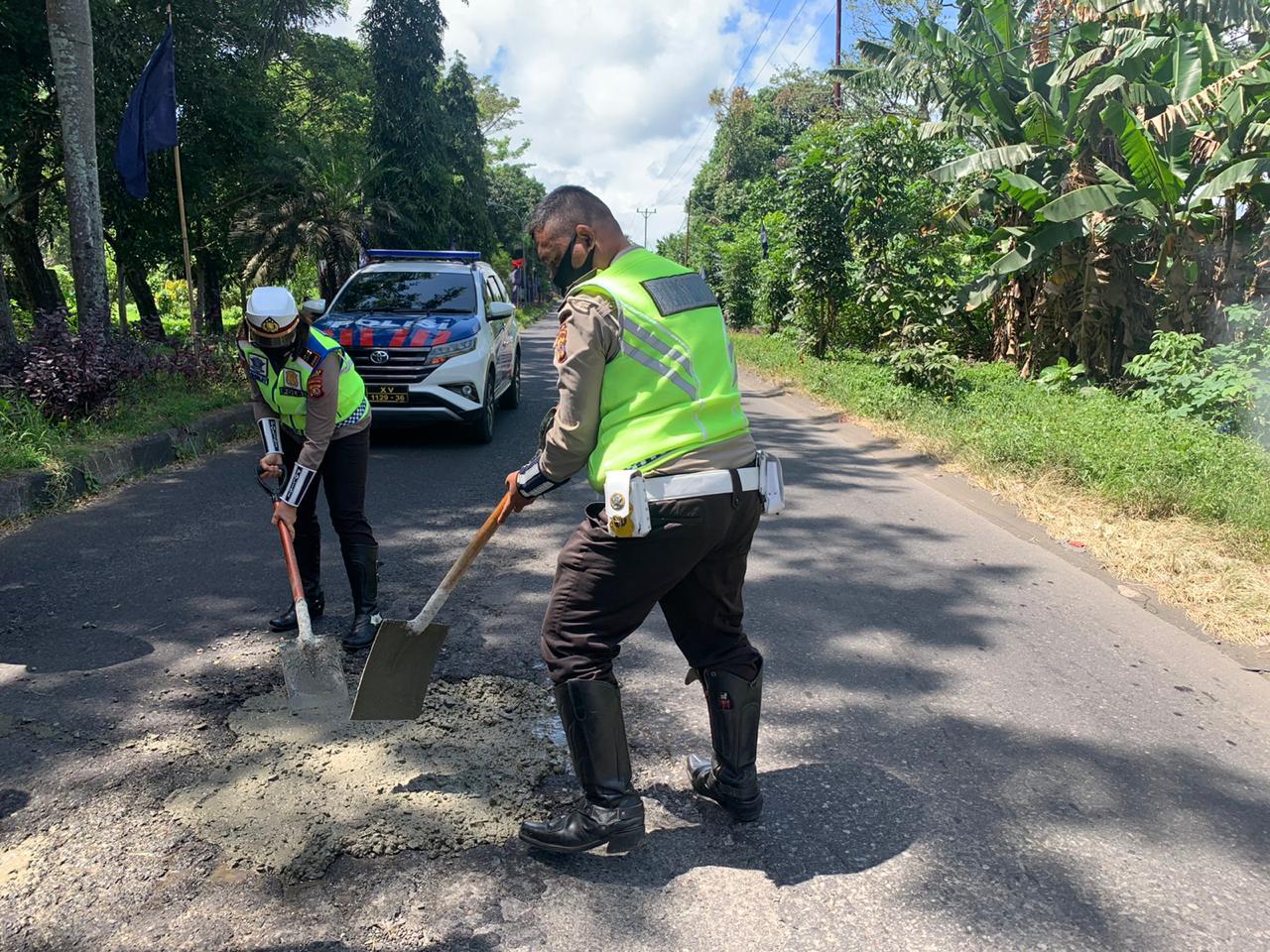 Satlantas Polres Minut saat menambal jalan berlubang di Depan SMK N 1 Airmadidi