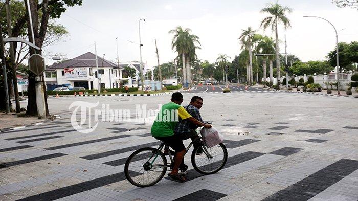 Sejumlah warga bersepeda melintasi proyek rekonstruksi intersection di Jalan Jenderal Sudirman simpang Jalan Ir H Juanda, Kecamatan Medan Polonia, Kota Medan, Rabu (13/12). Kepala Dinas SDABMBK Medan Topan Obaja Ginting mengatakan, proyek tersebut menggunakan teknis lama yaitu Rigid Beton (cetak beton) dan menghabiskan anggaran APBD Kota Medan sebesar Rp 1,7 Miliar.