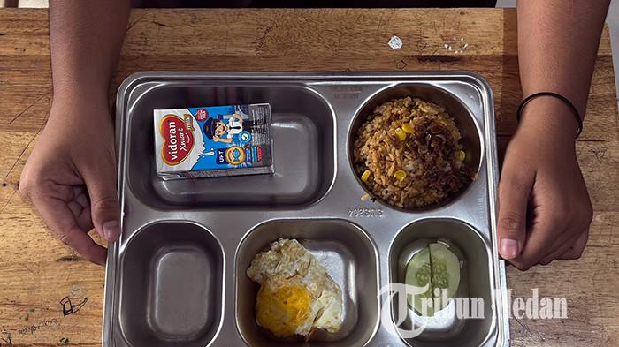 Siswa menunjukkan paket makanan program Makan Bergizi Gratis (MBG) yang diterimanya di SMA Negeri 21, Medan, Sumatra Utara, Jumat (17/10/2025). Menu spesial MBG kali ini nasi goreng telur ceplok yang disajikan serentak di seluruh Indonesia, bertepatan memperingati hari ulang tahun Presiden Prabowo.