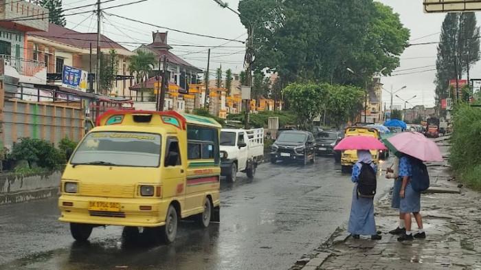 CUACA EKSTREM - Sejumlah pelajar tampak berlindung dari guyuran hujan menggunakan payung saat melintas di Jalan Jamin Ginting, Kabanjahe, Rabu (26/11/2025). Akibat cuaca ekstrem yang terjadi selama sepekan terakhir, BPBD Karo kembali mengimbau warga waspada terjadinya bencana hidrometrologi.