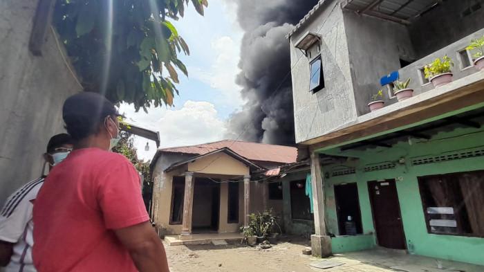KEBAKARAN PABRIK MAINAN - Warga melihat kepulan asap yang bersumber dari kebakaran pabrik mainan, di Jalan Sumber Amal, Kecamatan Medan Johor, Kota Medan, Minggu (21/6/2026). Hingga hari ini, kebakaran hebat yang terjadi sejak malam tadi masih belum benar-benar padam bahkan kembali membesar siang tadi.