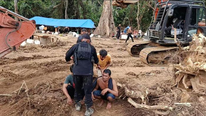 Momen Polisi mengumpulkan terduga pelaku penambang emas ilegal yang berhasil diamankan di pinggiran sungai Batang Gadis, perbatasan Tapanuli Selatan dengan Kabupaten Mandailing Natal, Senin (2/3/2026). Selain mengamankan 14 ekskavator, 7 orang turut ditangkap.