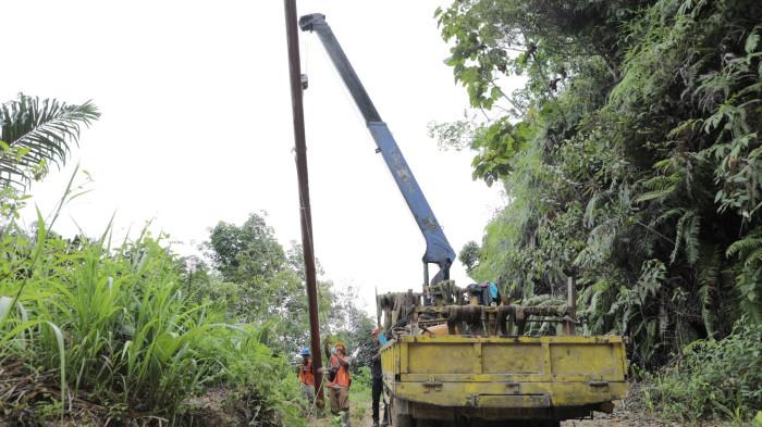 Pendirian tiang SUTM pada medan yang miring dengan menggunakan mobile crane.