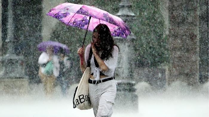 HUJAN LEBAT- Ilustrasi seorang wanita menggunakan payung sedang menembus hujan lebat yang melanda kawasan kota tempat tinggalnya.