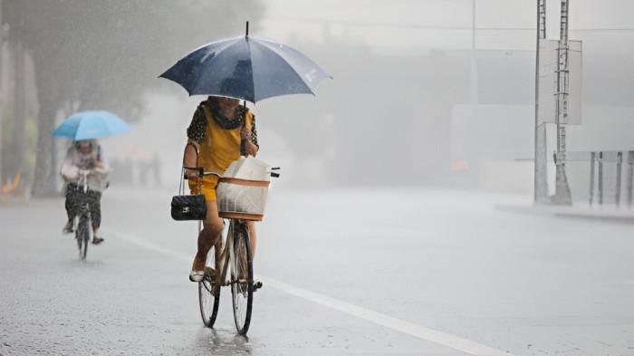 HUJAN DERAS- Ilustrasi seorang pengendara sepeda menembus hujan lebat dengan menggunakan payung.