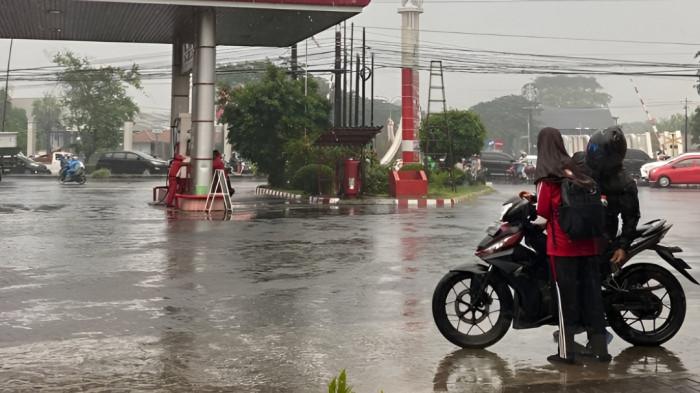 HUJAN- Ilustrasi pengendara motor tampak berhenti sejenak lantaran sempat diguyur hujan. Jalanan terlihat basah setelah hujan turun.