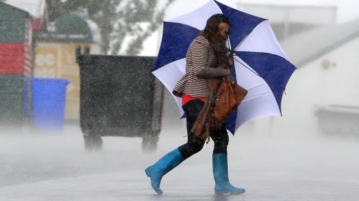 MENEMBUS HUJAN- Seorang wanita menggunakan payung berusaha menembus hujan.