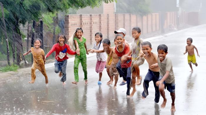 MANDI HUJAN- Sejumlah anak tampak girang bermain di tengah kondisi hujan lebat.Mereka asyik mandi hujan bersama teman di lingkungan tempat tinggalnya.