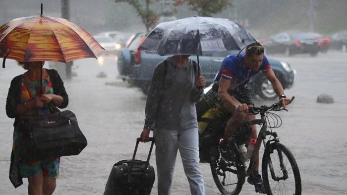 HUJAN- Sejumlah orang sedang terlihat menggunakan payung saat hujan.