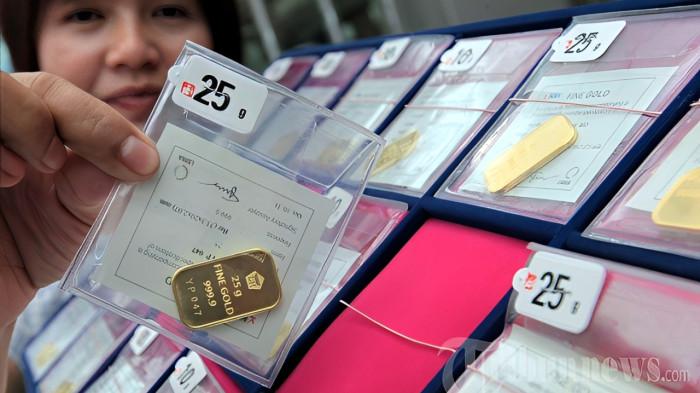 Seorang penjaga toko memperlihatkan emas batangan Antam di Toko Emas Buana, Jalan Ahmad Yani, Kosambi, Kota Bandung, Senin (10/3/2014). Dalam dua hari terakhir harga emas batangan Antam di pasaran anjlok hingga Rp 6.000 - 8.000 per gram, seperti di toko emas ini harganya turun dari Rp 495 ribu menjadi Rp 487 ribu per gram.