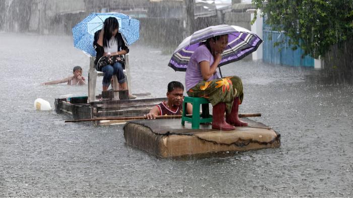 HUJAN LEBAT- Ilustrasi foto hujan lebat, dimana seorang pria tengah berusaha menyelamatkan seorang wanita dari kepungan banjir besar.