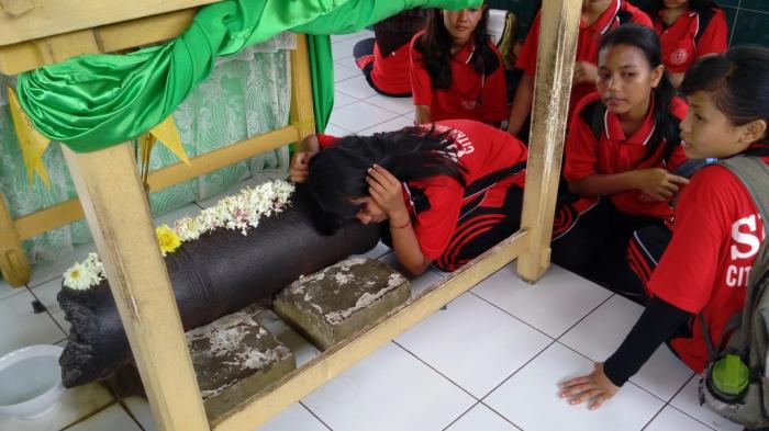 Pengunjung meriam puntung terlihat sedang menempelkan telinganya di badan meriam untuk mendengarkan suara lirih dari badan meriam