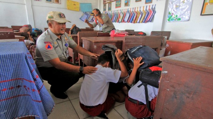 Sejumlah siswa SD melindungi kepala menggunakan tas saat simulasi penanggulangan bencana gempa di SD Negeri 060911 Menteng, Medan, Selasa (17/1/2017).