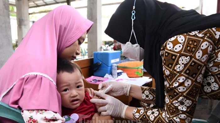 Bidan Desa Yudha Purwanidyah (kanan) menyuntikan vaksin kepada balita saat imunisasi di Posyandu Balai Desa Ngadilangkung, Kecamatan Kepanjen, Kabupaten Malang, Kamis (2/2/2023). Imunisasi tersebut dilakukan sebagai antisipasi untuk meminimalisir anak dari dampak terpapar campak. Pemerintah Kabupaten Malang melalui Dinas Kesehatan (Dinkes) Kabupaten Malang mengimbau para orang tua untuk segera membawa putra-putrinya melakukan imunisasi terutama untuk imunisasi campak. Baik melalui posyandu, puskesmas atau bisa dilakukan di sekolah dasar (SD) secara gratis. SURYA/PURWANTO