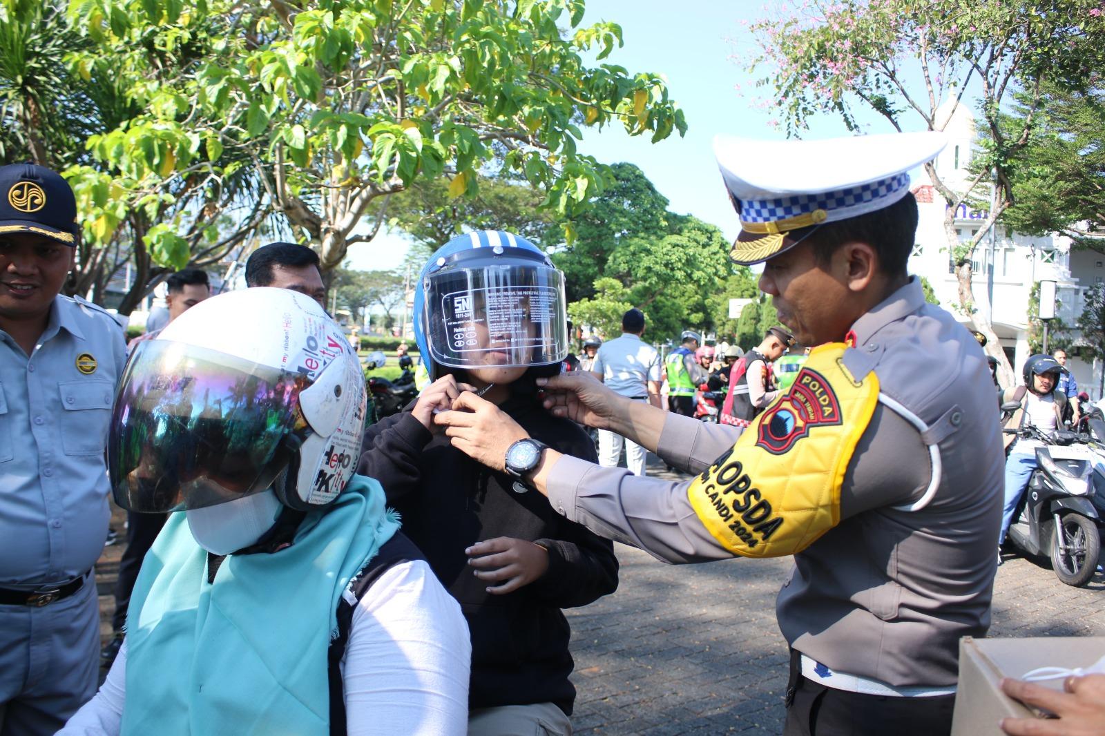 Petugas-kepolisian-memakaikan-helm-kepada-pembonceng-sepeda-motor.jpg