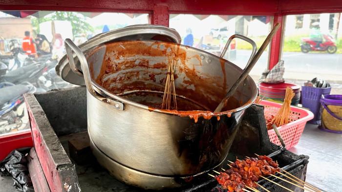 SATE DI TAPLAU- Senja di Pantai Padang selalu punya cara sendiri memanggil orang datang. Bukan hanya lewat warna langitnya, tetapi juga melalui aroma sate padang yang mengepul dari kuali-kuali panas di tepi laut, menyatu dengan debur ombak dan hiruk-pikuk Taplau.
