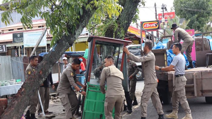 PENERTIBAN LAPAK PKL - Satpol PP Padang menertibkan sejumlah lapak PKL yang ditinggal usai berjualan di trotoar dan badan jalan kawasan Jalan Sutan Syahrir, Kecamatan Padang Selatan, Rabu (22/10/2025) pagi.