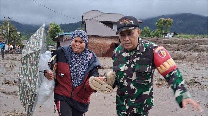 BANJIR BANDANG- Prajurit TNI saat membantu seorang warga melewati lumpur yang terbawa banjir bandang di Jorong Toboh, Nagari Malalak Timur, Kecamatan Malalak, Kabupaten Agam, Rabu (26/11/2025). 