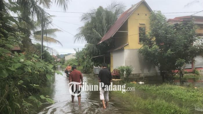 BANJIR- Penampakan warga yang sedang berjalan di tengah genangan banjir di Gang Babussalam I, Jalan DPR Ujung, Kelurahan Dadok Tunggul Hitam, Kecamatan Koto Tangah, Kota Padang, Sumatera Barat, Jumat (21/11/2025).
