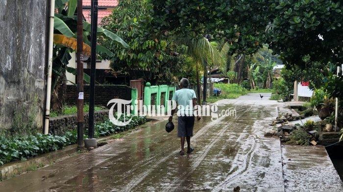 BANJIR- Warga melintasi jalan yang dipenuhi lumpur dan kondisi licin usai banjir merendam kawasan Jondul Raya, Rawang, Padang Selatan, Jumat (21/11/2025). Diketahui kawasan ini direndam banjir pada dini hari tadi.