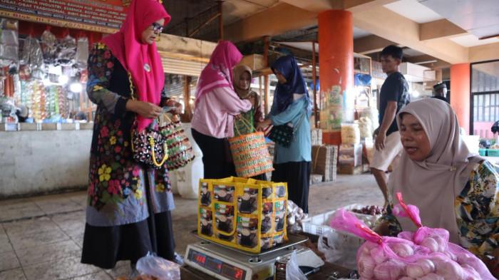 HARGA PLASTIK: Salah satu warga di Pasar Raya belanja menggunakan Keranjang  unik karena terbuat dari rangkaian mulut atau lingkaran gelas plastik bekas minuman ringan. Senin (13/4/2026). Konstruksi dari lingkaran plastik yang keras membuat keranjangnya sangat awet dan mampu menahan beban belanjaan yang berat.