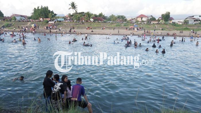 WISATA DADAKAN- Penampakan masyarakat ramai mengunjungi lokasi aliran sungai yang menjadi wisata dadakan di Jembatan Ujung Tanah, Kecamatan Lubuk Begalung, Kota Padang, Senin (12/1/2026) sore.