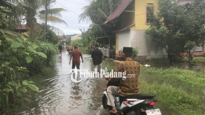 BANJIR DI PADANG- Beberapa warga saat melewati jalan yang digenangi air di Kelurahan Dadok Tunggul Hitam, Kecamatan Koto Tangah, Kota Padang, Sumatera Barat, Jumat (21/11/2025).