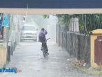 seorang-remaja-mengayuh-sepeda-saat-hujan-turun.jpg